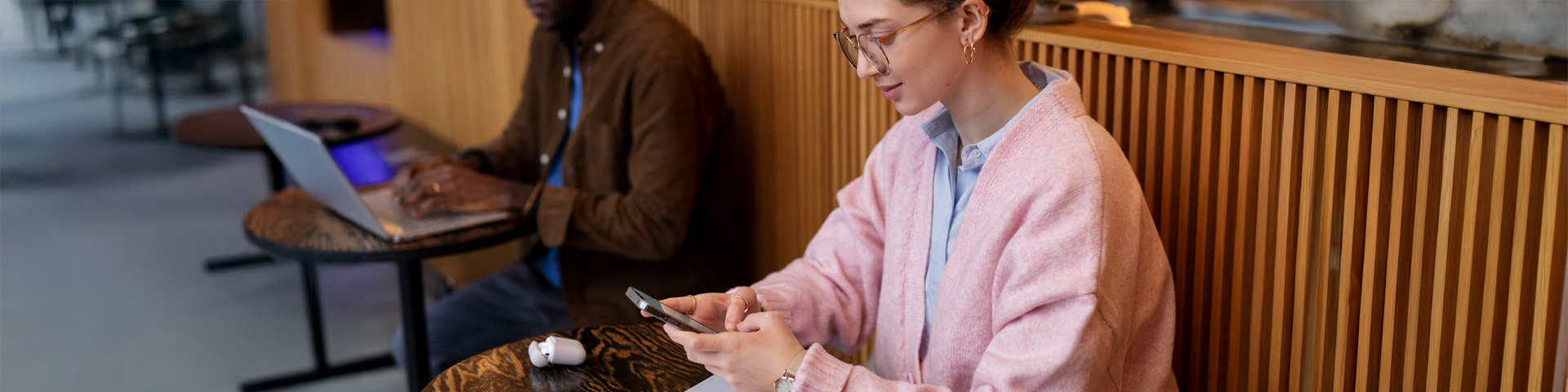 young lady sitting inside restaurant with mobile phone in hands