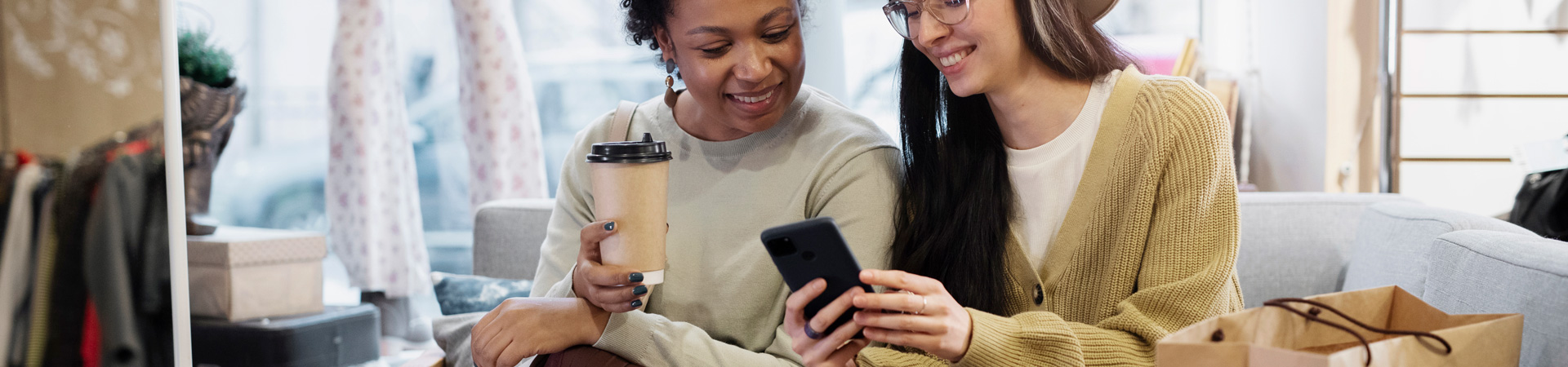 ladies looking at mobile phone and smiling during shopping trip