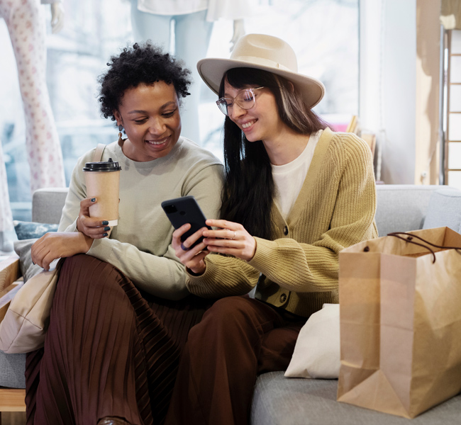 ladies looking at mobile phone and smiling during shopping trip