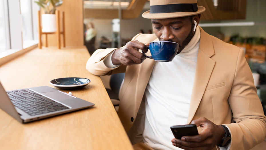 man drinking coffee and looking at his phone in a cafe